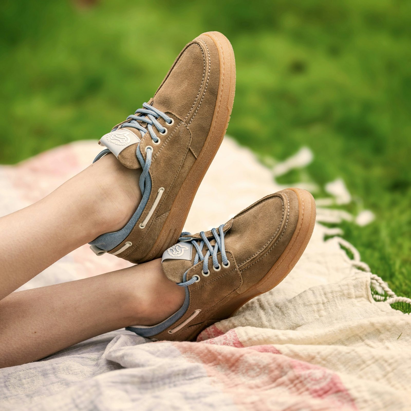 Stylish shoes resting on a blanket in grass.